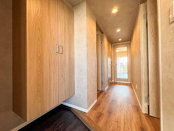 新規交換された建具と床が美しい、明るく上品な印象で家族やゲストを迎える玄関アプローチ。