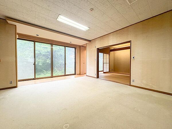 大きな窓から豊かな緑と光が差し込む、開放的な居室です。隣接する和室と合わせて、家族の団らんや、お子様の遊び場としても多目的に活用できます。