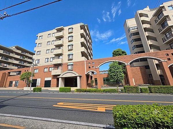 重厚感のあるタイル貼りの外観とアーチ形のエントランスが印象的なマンションです。手入れの行き届いた植栽が街並みに彩りを添え、ゆとりある敷地計画が落ち着いた住環境を演出します。