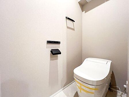 スタイリッシュな温水洗浄便座付きトイレ。黒のペーパーホルダーがお洒落な空間です。
