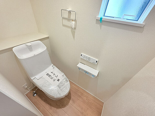 トイレには温水洗浄便座を備え、快適に使える設備が整っています。窓付きのため自然光を取り込みやすく、換気にも便利です。背面にはカウンターを設け、予備のペーパーや小物類を置ける実用的な空間です。