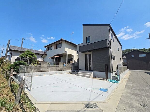 角地に建つ新築住宅は、道路側にゆとりのあるカースペースを確保しています。建物の二方向が道路や開けた空間に面し、開放感を感じられる配置です。玄関までの動線も確認しやすく、住まいの雰囲気が伝わる外観です。