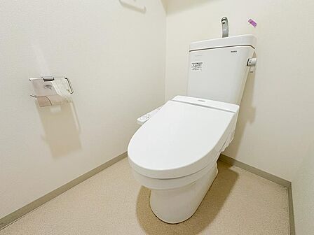 白を基調とした、すっきり清潔感のあるトイレ。温水洗浄便座を備え、毎日気持ちよく使用できます。タンク上部には手洗いも設けられており、省スペースながら使いやすさに配慮された快適な空間です。