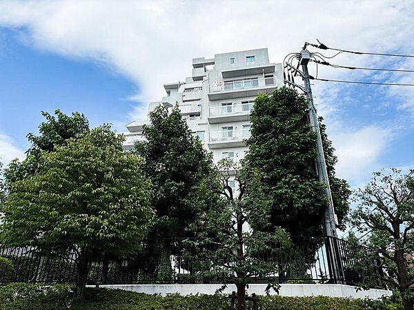 空の青と建物の白、そして豊かな緑のコントラストが美しい外観。自然を感じながら、家族との穏やかな時間を過ごせる住まいです。