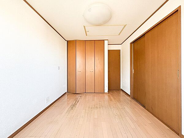 陽光差し込む明るい洋室。木目調フローリングと白壁が清潔感を演出する、心地よいプライベート空間です。