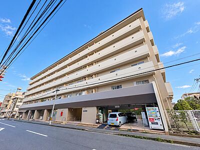 外観:落ち着いたベージュトーンの外観デザインが特徴的なマンションです。1階部分には平置きの駐車スペースやアプローチが整えられており、前面道路からの出し入れや移動もスムーズに行えます。 外観:落ち着いたベージュトーンの外観デザインが特徴的なマンションです。1階部分には平置きの駐車スペースやアプローチが整えられており、前面道路からの出し入れや移動もスムーズに行えます。