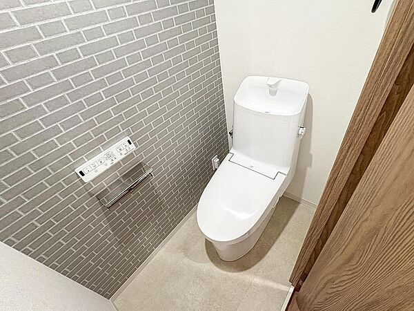 スタイリッシュなレンガ調の壁が印象的なトイレ空間。最新の設備で、家族みんなが清潔で快適に利用できるプライベートな場所です。