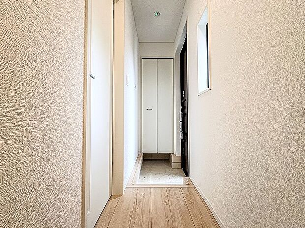 玄関から室内へとまっすぐ伸びる清潔感あふれる廊下空間。突き当たりの収納棚や明るい壁面・フローリングが開放感を出し、帰宅時も優しく温かく迎えてくれる心地よい導線デザインです。