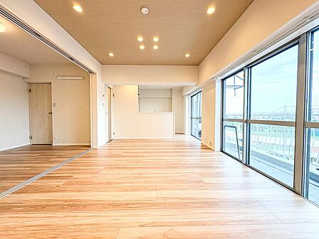大きな窓から豊かな光が注ぎ込む、開放感あふれるリビングです。バルコニーに面した伸びやかな空間と、木の温もりを感じる美しいフローリングが調和し、家族が自然と集まりたくなる心地よさを演出します。