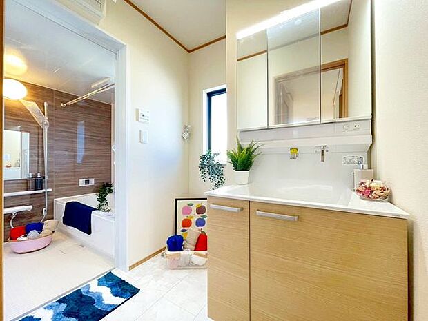 【洗面室】シャワー機能付きの洗面台には使いやすい横長ボウル、スマートに収まる収納と充実しています。あわただしい朝の洗面タイムに心強い設備です。