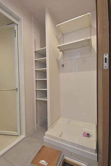 洗剤やタオル類をすっきり整理できる吊戸棚と収納を設置した洗濯機置き場。