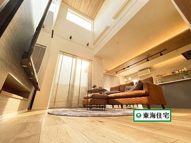 吹抜リビングは、フローリングの木の質感や、ブラインド越しに入る柔らかな光の美しさを引き立てます。