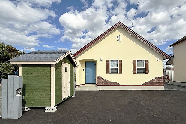 まるで絵本から抜け出したような、やさしいアイボリーの外壁にレンガがレトロなアクセント。小さなグリーンの物置も、暮らしを楽しく彩ります。