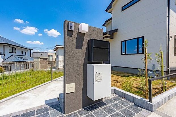 【 玄関アプローチ 】玄関へ続くアプローチには、宅配ボックス付き機能門壁を設置。また、庭部分には天然芝が敷き詰められ、豊かな緑を楽しむ一時も。