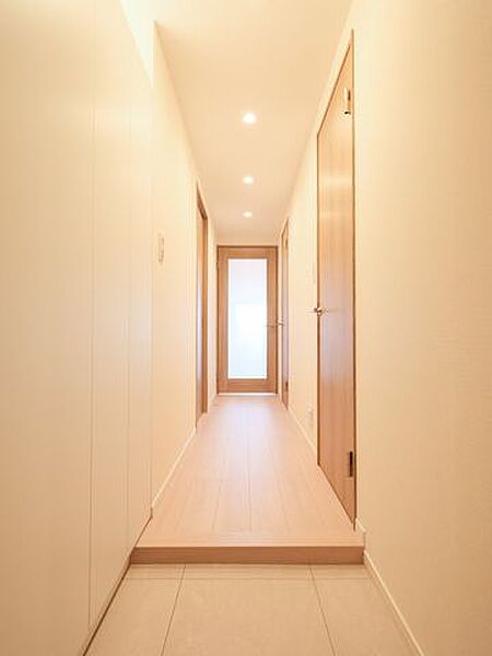 淡い木目と白い壁が調和した玄関です。ガラス扉がもたらす抜け感により、より広がりを感じられる空間に仕上がっています。