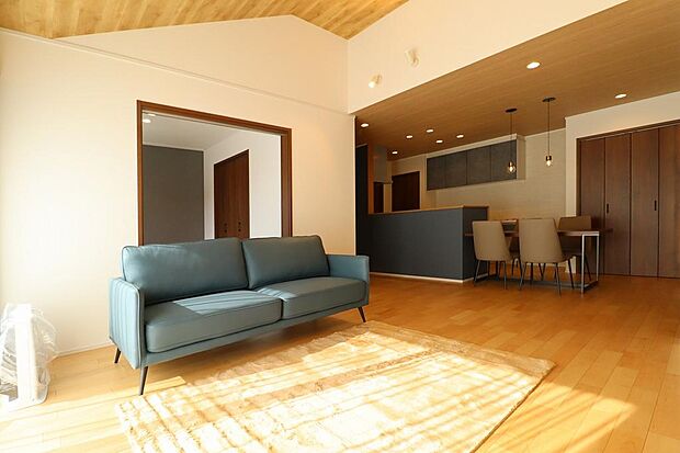 リビングは天井勾配で、天井は木目調になって落ち着いた雰囲気です。天井を照らす照明で間接的に光を出すことでお洒落な演出です。掃き出し窓の外にはウッドデッキも付いています。リビング隣接には和室もあります。