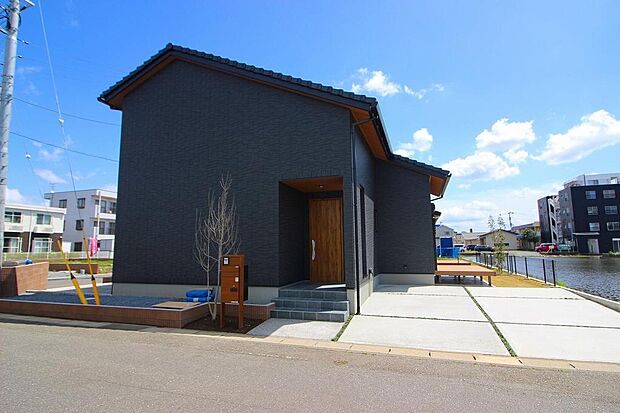 玄関側の外観です。黒いタイルがシックで木目調の玄関ドアが目を引きます。車も2台駐車可能です。