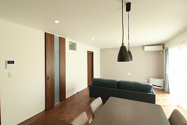 リビングのアクセントクロスがお洒落です。室内にあるカーテン、照明、家具はそのままのお引き渡し。床材もシックな色合いで落ち着いたリビングになっています。