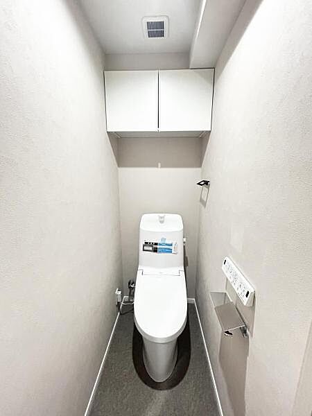 上部に吊戸棚を配し、限られた空間をすっきりと使える清潔感のあるトイレ。