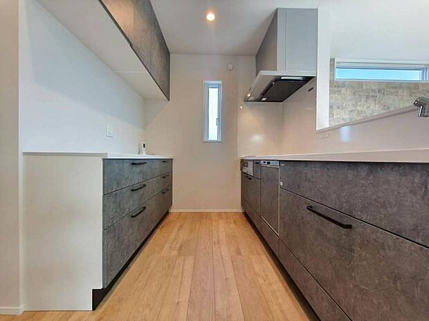 キッチン背面にキッチンと同色の面材を使用したカップボードを設置し収納力と統一感を高めています。