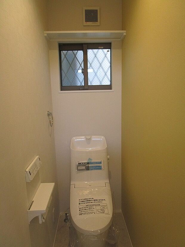 ２階のトイレ：温水洗浄便座付きのトイレです。上部に収納棚があり便利です。換気扇や窓があります。