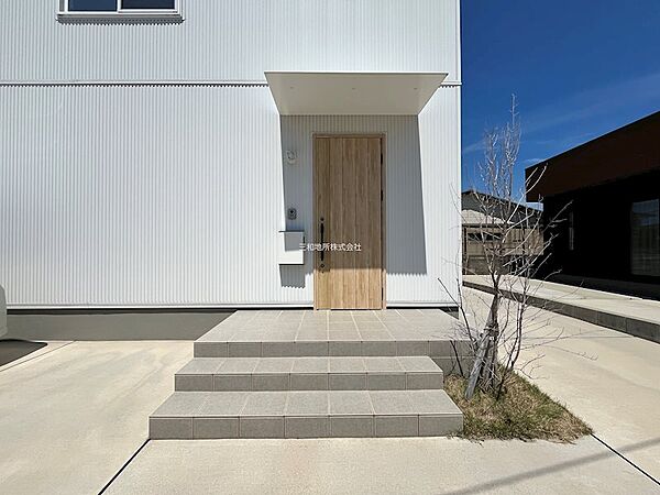 白い外壁に木目調のドアが温かみを添え訪れる人を優しく迎え入れます