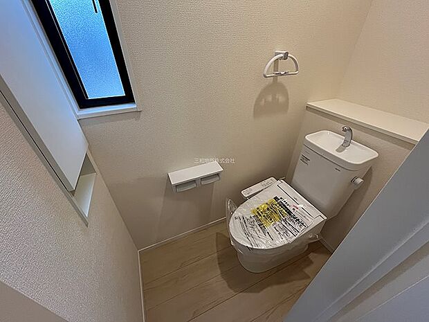 窓から光が差し込む明るい2Fトイレ。上部に扉付きの棚も備え付けられ機能性も兼ね備えています。
