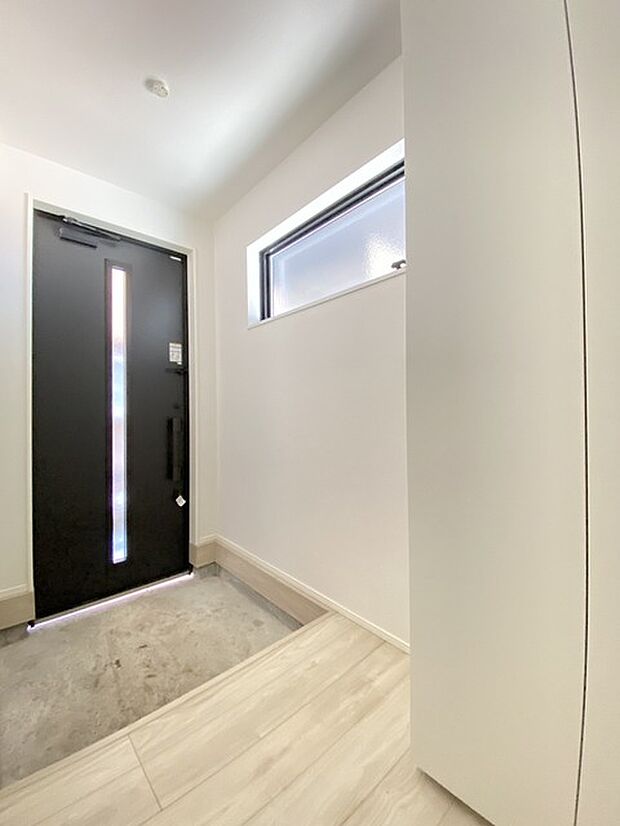 収納と窓のある機能的な玄関。上り框は低めになっています。