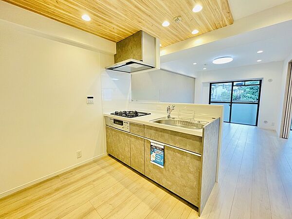 木目の折り上げ天井が空間に柔らかな奥行きをもたらし、洗練された素材感と住まい全体が心地よく調和する、落ち着いた暮らしの場です