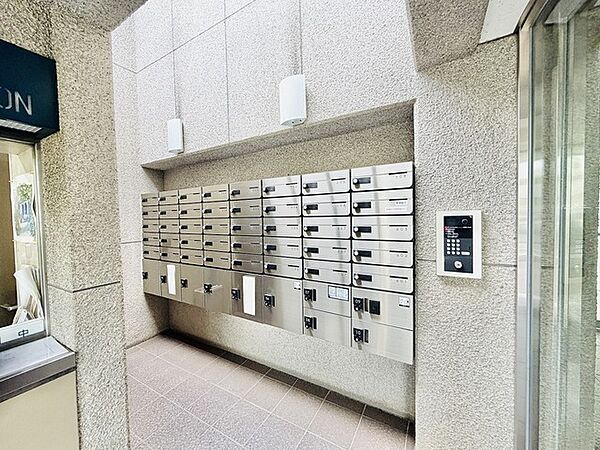 重厚感のある石目調の壁面と機能的な集合ポストが調和する、落ち着いた佇まいのエントランスです