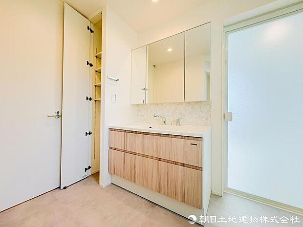 【洗面化粧台】 三面鏡裏収納付き洗面化粧台。身支度用品をすっきり収納でき、脱衣スペースも広く確保された快適な洗面空間です。