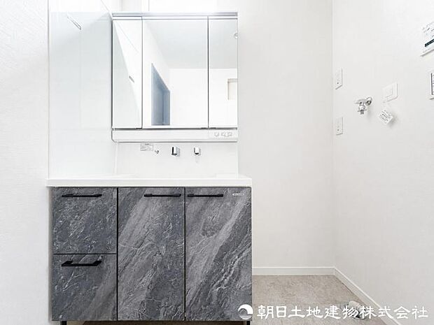 【洗面化粧台】 三面鏡裏収納付き洗面化粧台。身支度用品をすっきり収納でき、脱衣スペースも広く確保された快適な洗面空間です。