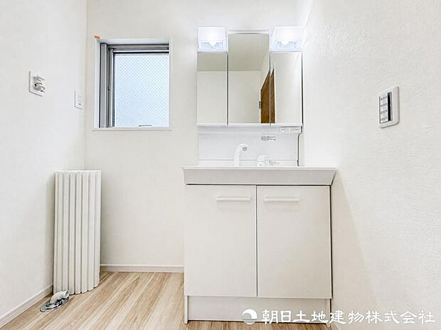 【洗面化粧台】 三面鏡裏収納付き洗面化粧台。身支度用品をすっきり収納でき、脱衣スペースも広く確保された快適な洗面空間です。