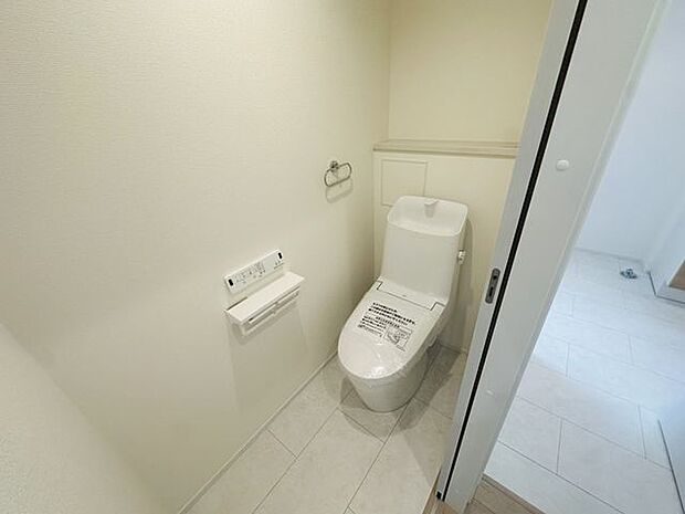 【2階トイレ】年間を通して快適に使用できる温水洗浄便座付きトイレ。壁付けタイプのリモコンが設置されています。