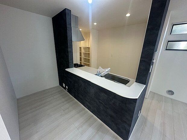 【キッチン/1号棟】シックな色調でまとめられたキッチン。料理の配膳や後片付けの動線も、カウンターを経由すればスムーズです。