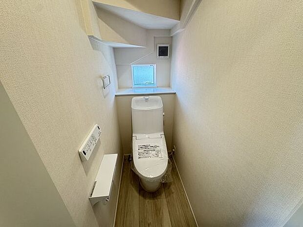 【1階トイレ/2号棟】自然光が入る窓付きトイレです。温水洗浄便座が備わり、寒い時期でも快適に使用できます。操作しやすい壁面リモコンが採用されています。