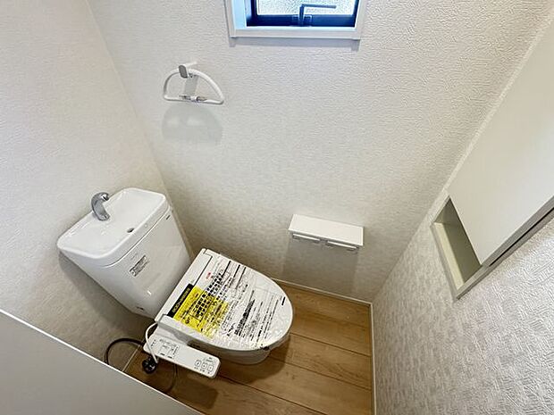 【1階トイレ/2号棟】小窓が設けられており、採光・換気が可能。トイレットペーパーや掃除用具などをしまえる収納棚が備わっています。