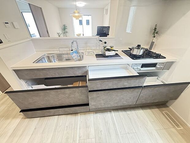 【1号棟/キッチン】キッチン前面に腰壁が施され、散らかりがちな手元が見えにくい仕様。調理家電用のコンセントも設置されています。※家具調度品等は販売価格に含まれません。