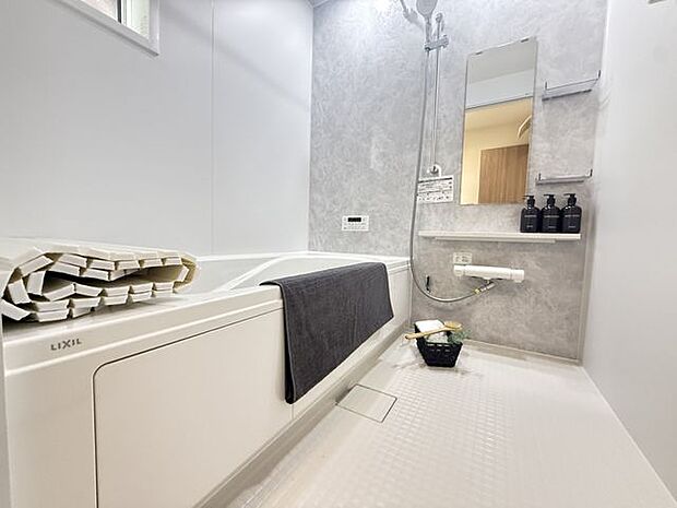 【1号棟/浴室】アクセントパネルが施され、落ち着いた雰囲気。シャワーの高さ調節ができるスライドバーや、シャンプー類を置ける棚が備わっています。※家具調度品等は販売価格に含まれません。