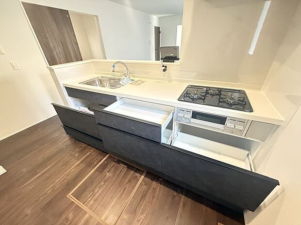 【2号棟/キッチン】キッチン前面に腰壁が施され、散らかりがちな手元が見えにくい仕様。調理家電用のコンセントも設置されています。