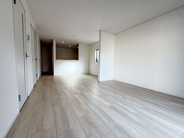 【LDK/約20帖/1号棟】ダイニングテーブルとソファを置いてもゆとりのある、広さ約20帖のLDKです。リビングからキッチンの様子が見えるので、ご家族どうしで会話が弾みやすい間取りです。