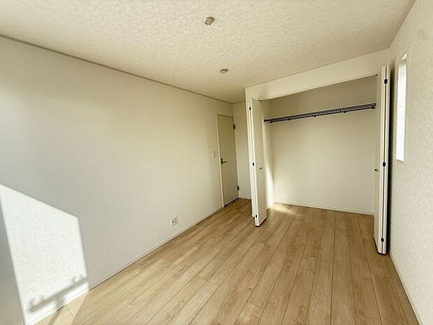 【洋室/約6.5帖/1号棟】南西バルコニーに面する掃き出し窓から、明るい陽光が注ぎ込みます。白を基調とした内装で、明るく清潔感のある住空間となっています。