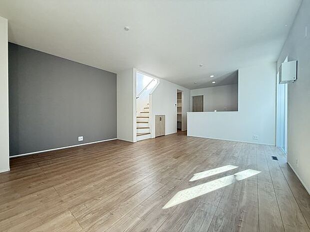 【LDK/1号棟】穏やかな色合いのアクセントクロスが、おしゃれな雰囲気。ご家族が顔を合わせやすいリビング階段が採用されています。