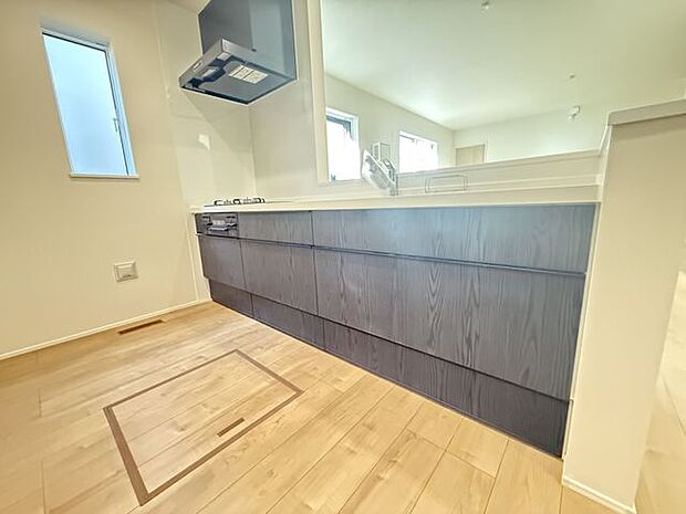 【キッチン/1号棟】木目調デザインのスタイリッシュなシステムキッチンです。食品ストックなどの収納に便利な床下収納が備わっています。