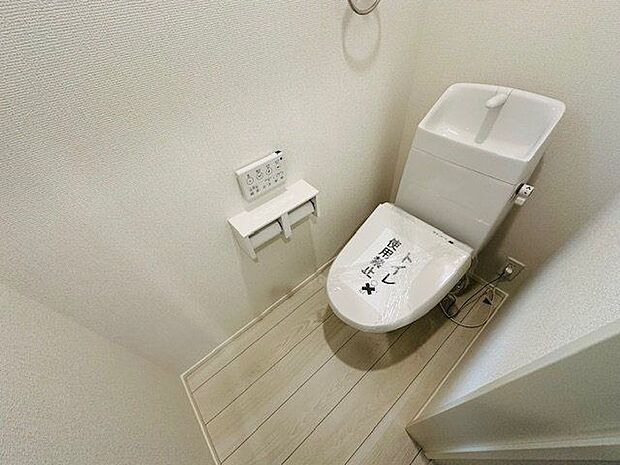 【1階トイレ/1号棟】温水洗浄便座が備わり、1年を通じて快適に使用できます。操作しやすい壁面リモコンが採用されています。