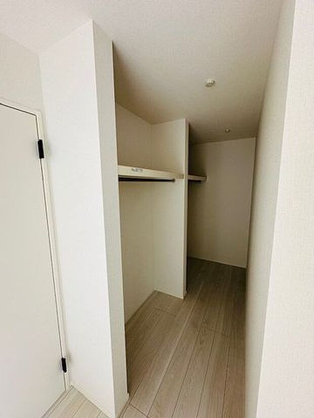 【洋室(約9帖)/1号棟】収納力のあるウォークインクローゼットが備わっています。ハンガーパイプと枕棚付きで、衣類や季節用品などがすっきりと片付きます。