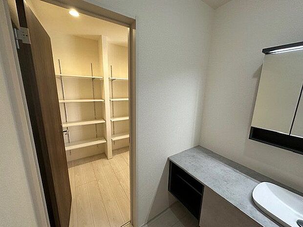 【洗面室/1号棟】洗面室からパントリーを経由してキッチンまでアクセス可能です。便利な回遊動線が採用されています。