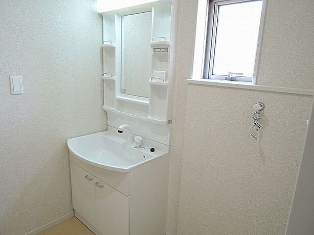 【洗面室/同仕様】窓から自然光が入る洗面室。洗濯機置場が設けられ、使い勝手の良いレイアウトが採用されています。清潔感のある白を基調とした内装です。※実際とは異なる場合があります。