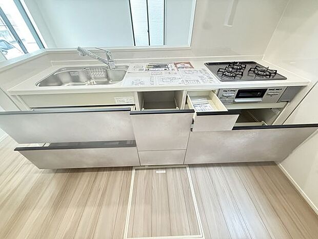 【キッチン/1号棟】天板下部にスライド式収納があるため、毎日の調理や片付けがスムーズです。ストック類や飲み物などの収納に便利な床下収納付きです。