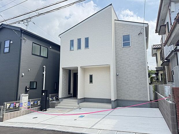 【外観/1号棟】明るい外壁が青空に映える住まいです。玄関上部には屋根があり、雨の日も落ち着いて傘を準備することができます。